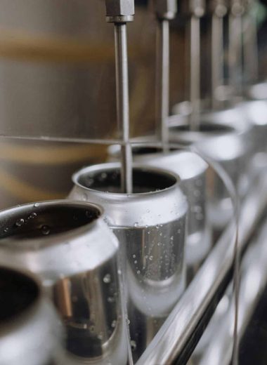 Detailed view of an industrial canning process with aluminum cans on an automatic assembly line.