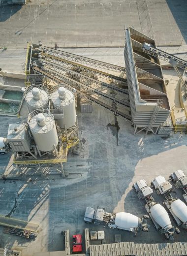 A drone-captured aerial view of an industrial concrete mixing plant with trucks and machinery.